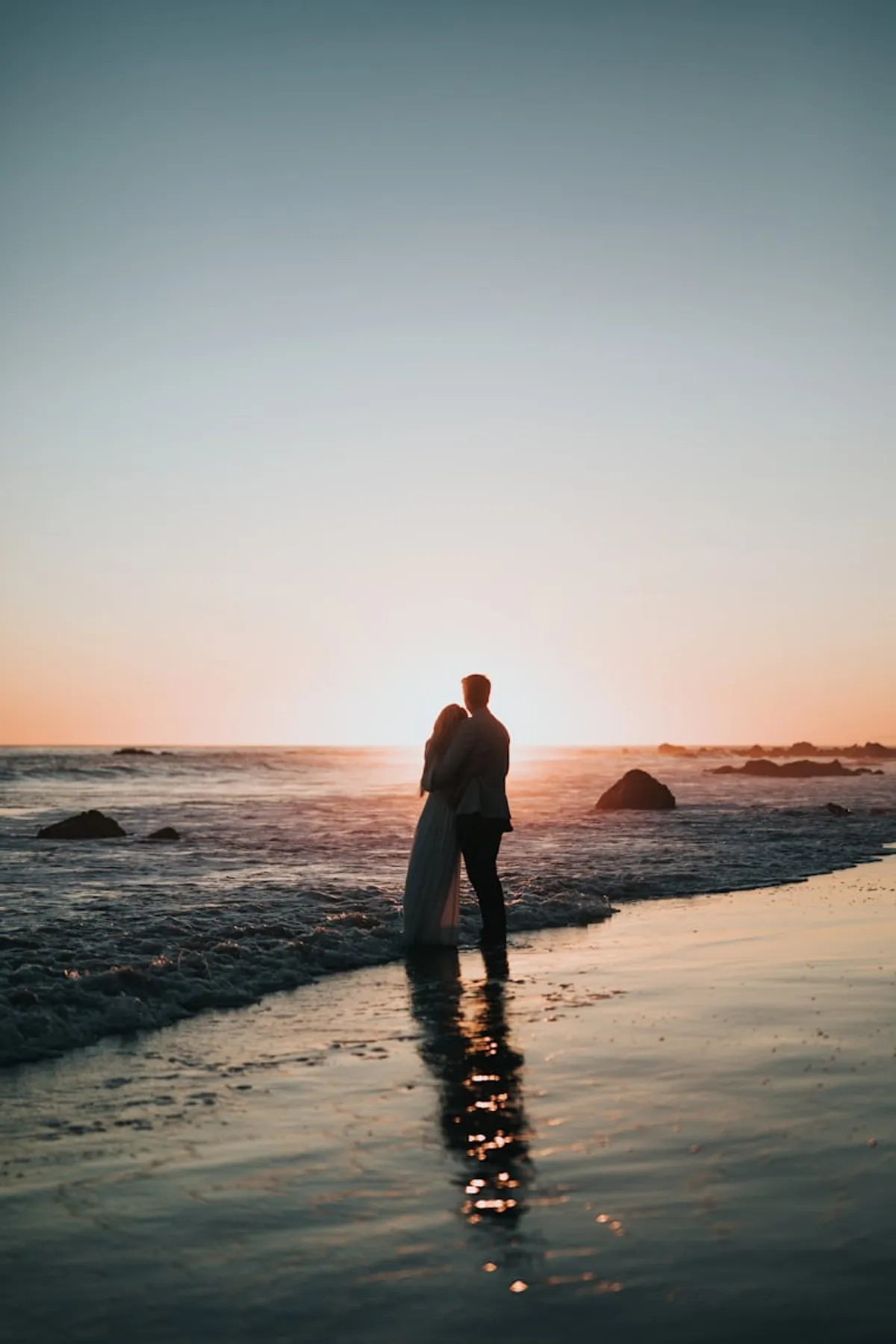 A couple standing at the waterline at sunset