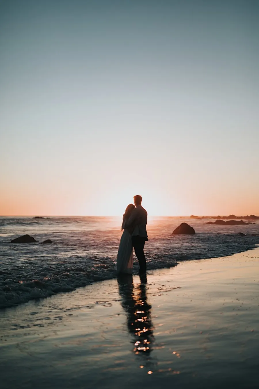 A couple standing at the waterline at sunset