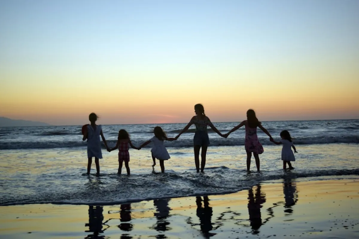A family holding hands at the waterline at sunset