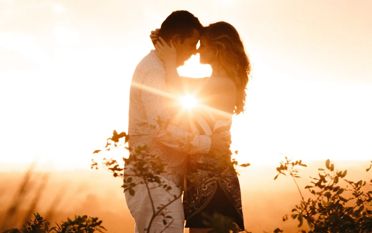 A couple embracing at sunset, the sun glowing between them