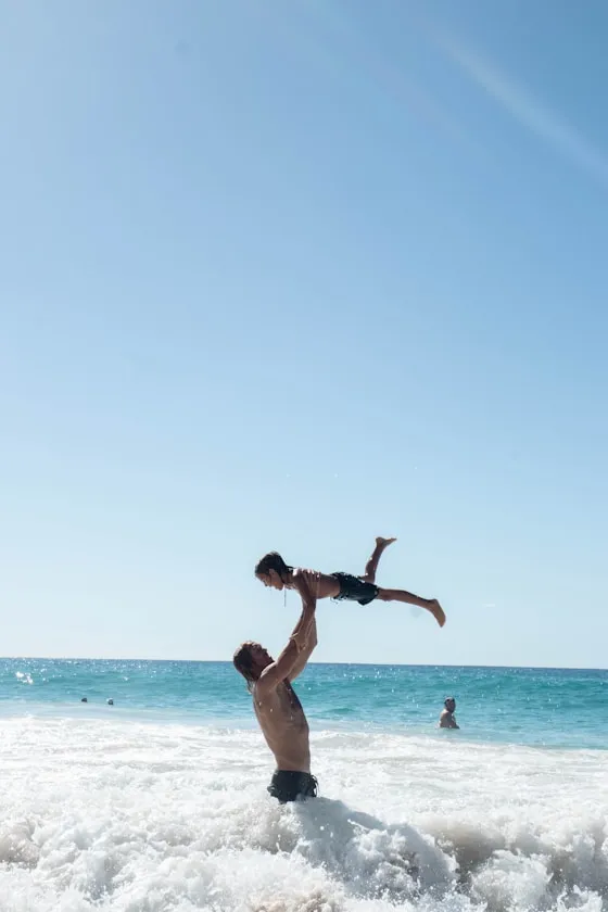 A dad tossing a kid over the waves